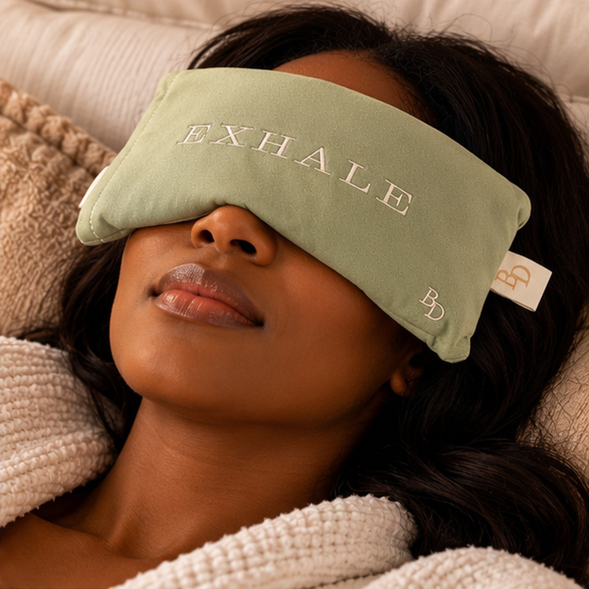 Woman resting with sage EXHALE Weighted Eye Pillow placed over her eyes.