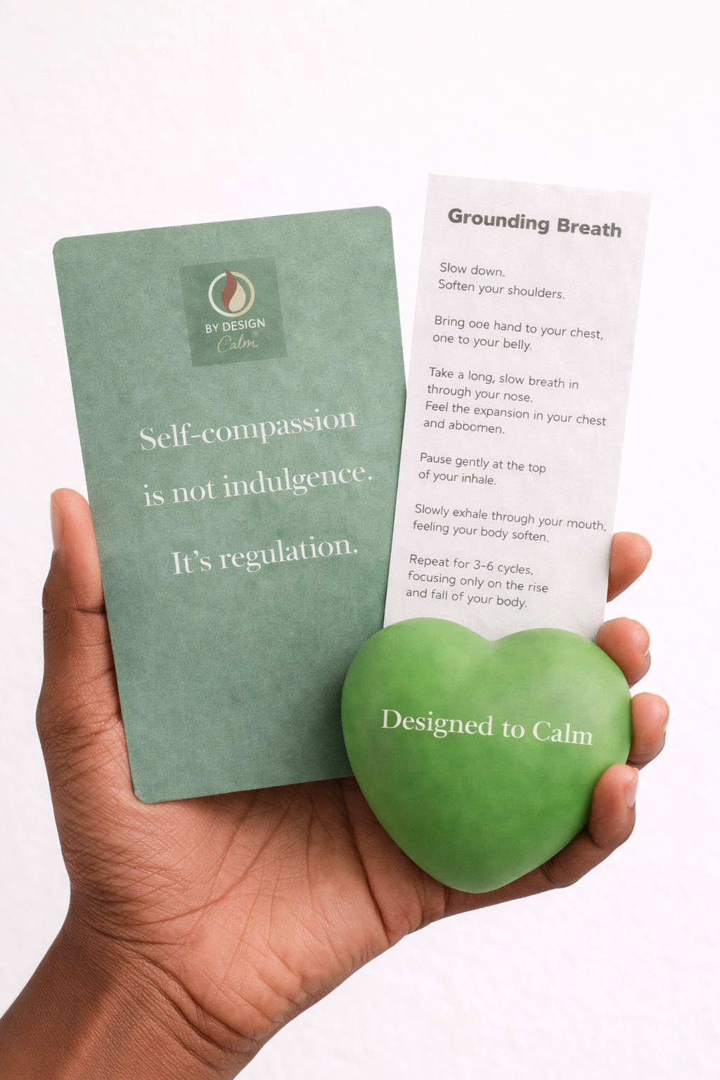 Hand holding a green stress ball with a card and a piece of paper on a white background