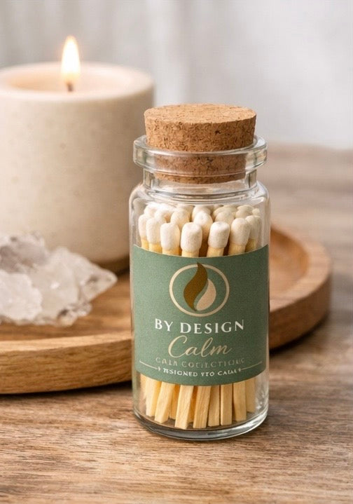 Jar of matches labeled 'By Design Calm' with a candle and crystal in the background.