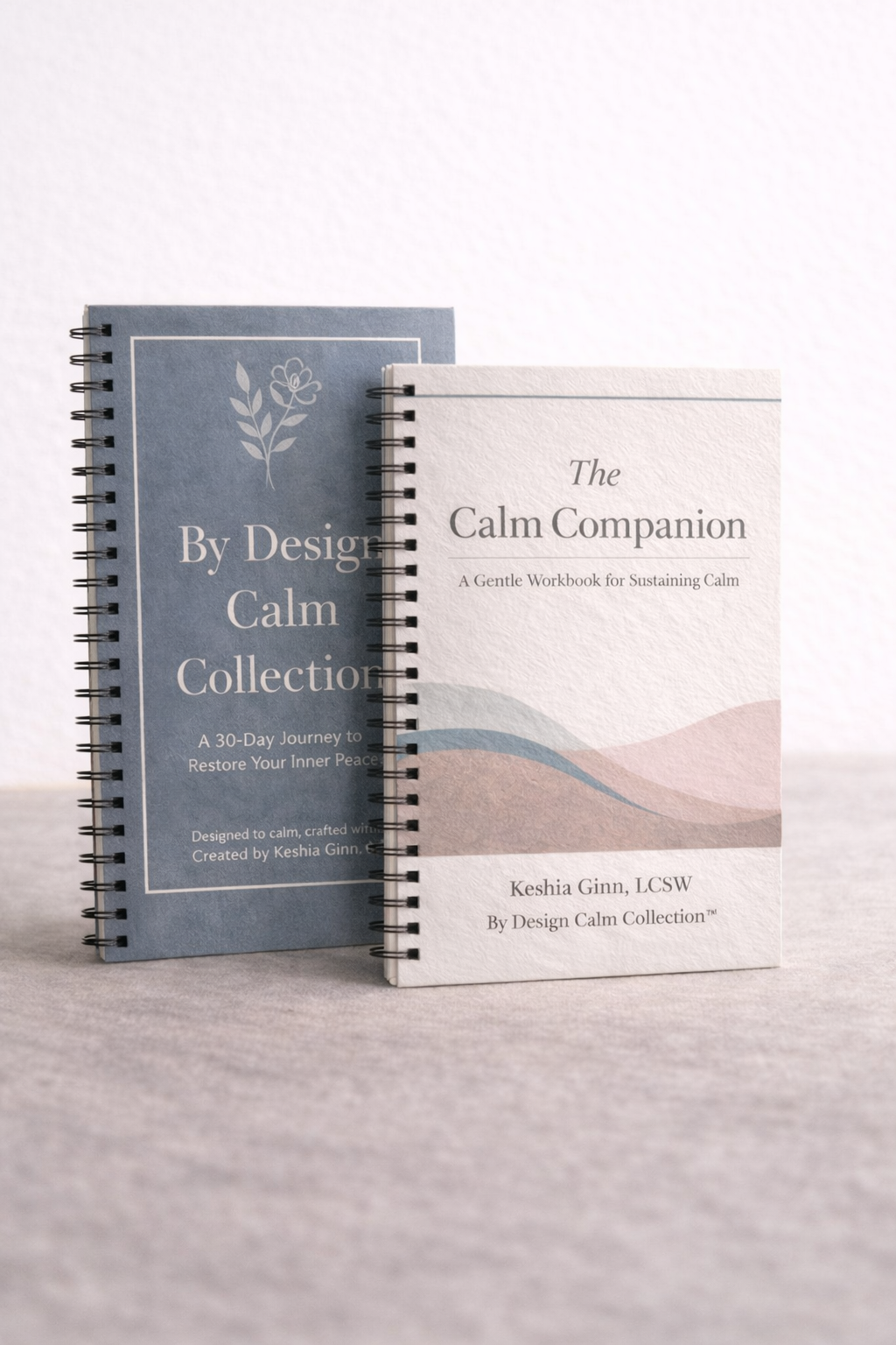 Two spiral-bound books titled 'By Design Calm Collection' and 'The Calm Companion' on a light gray surface.