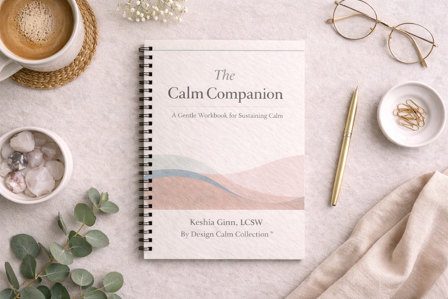 Spiral-bound book titled 'The Calm Companion' on a light surface with a cup of coffee, glasses, and eucalyptus leaves.